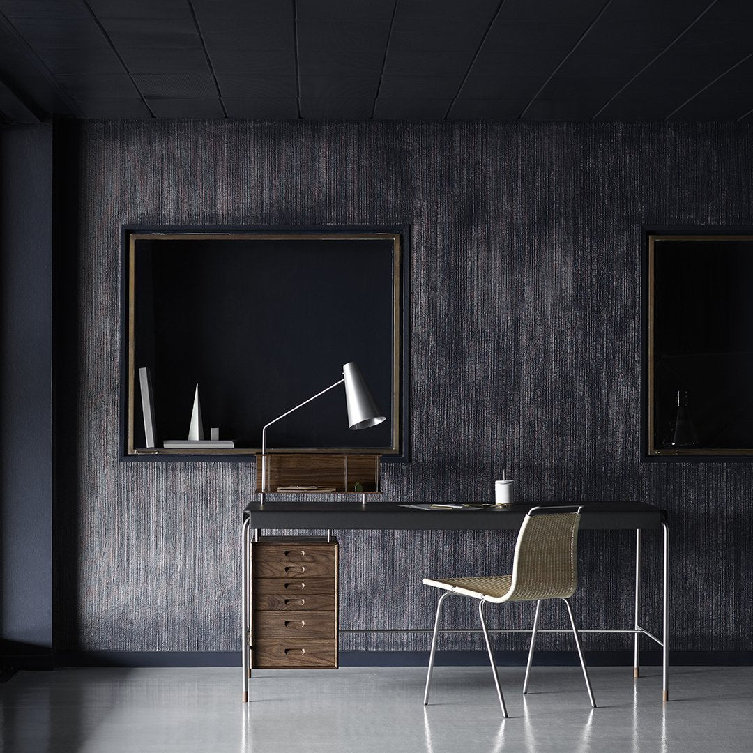 Modern workspace featuring dark textured walls, sleek black furniture, and a light-colored chair.