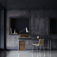 Modern workspace featuring dark textured walls, sleek black furniture, and a light-colored chair.