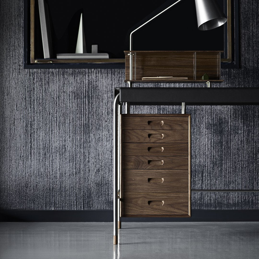 Modern brown wooden desk with sleek metal accents against a textured gray wall, minimalistic design elements.