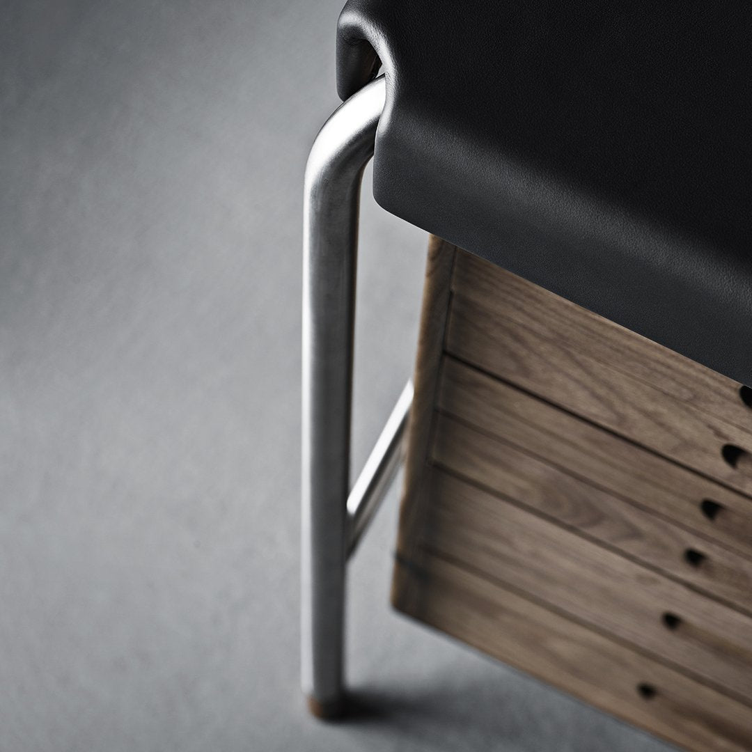 Black seat cushion with sleek silver metal legs and textured wooden storage, set against a grey backdrop.