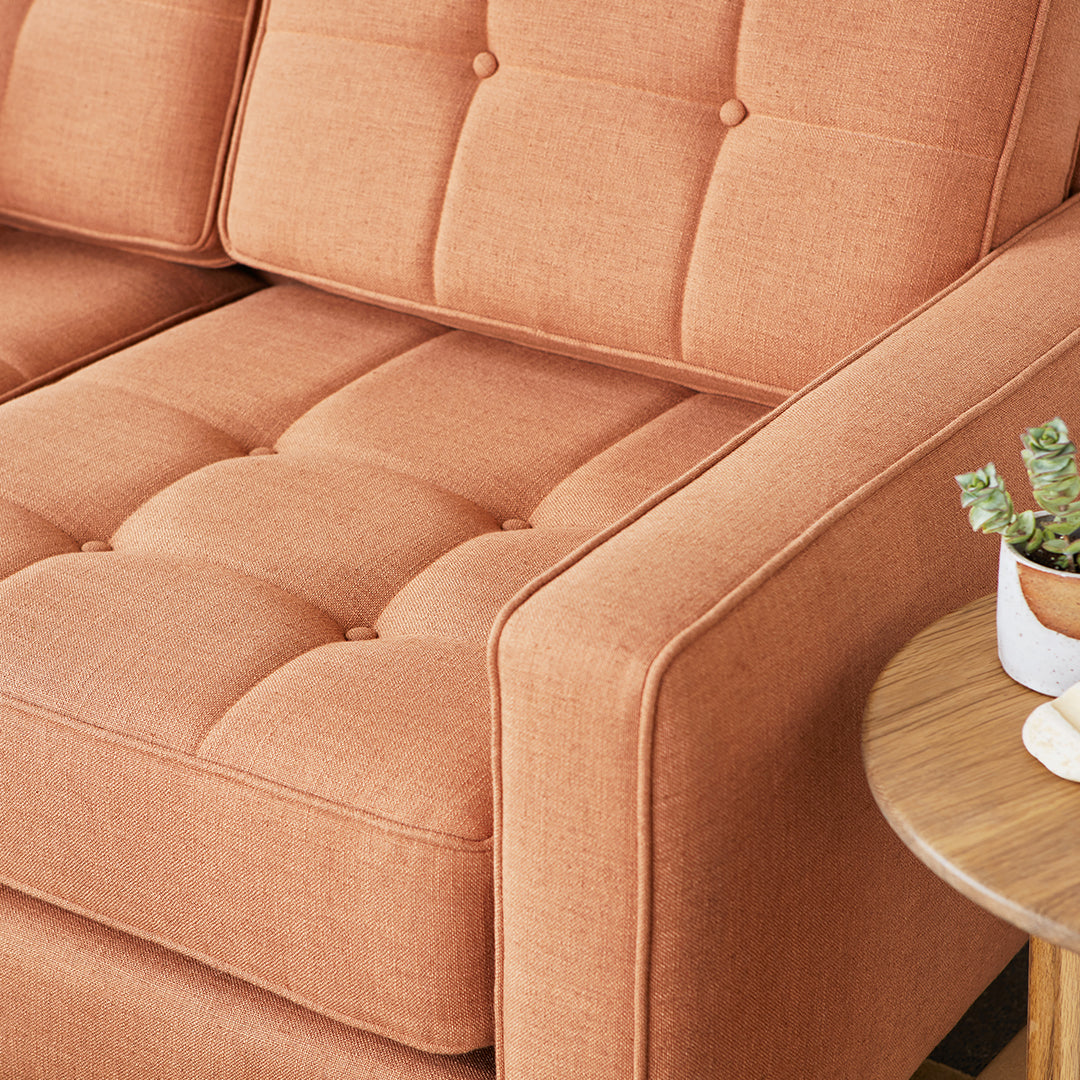 Textured orange sofa with tufted design, perfect for modern living spaces. Elegant and inviting upholstery.