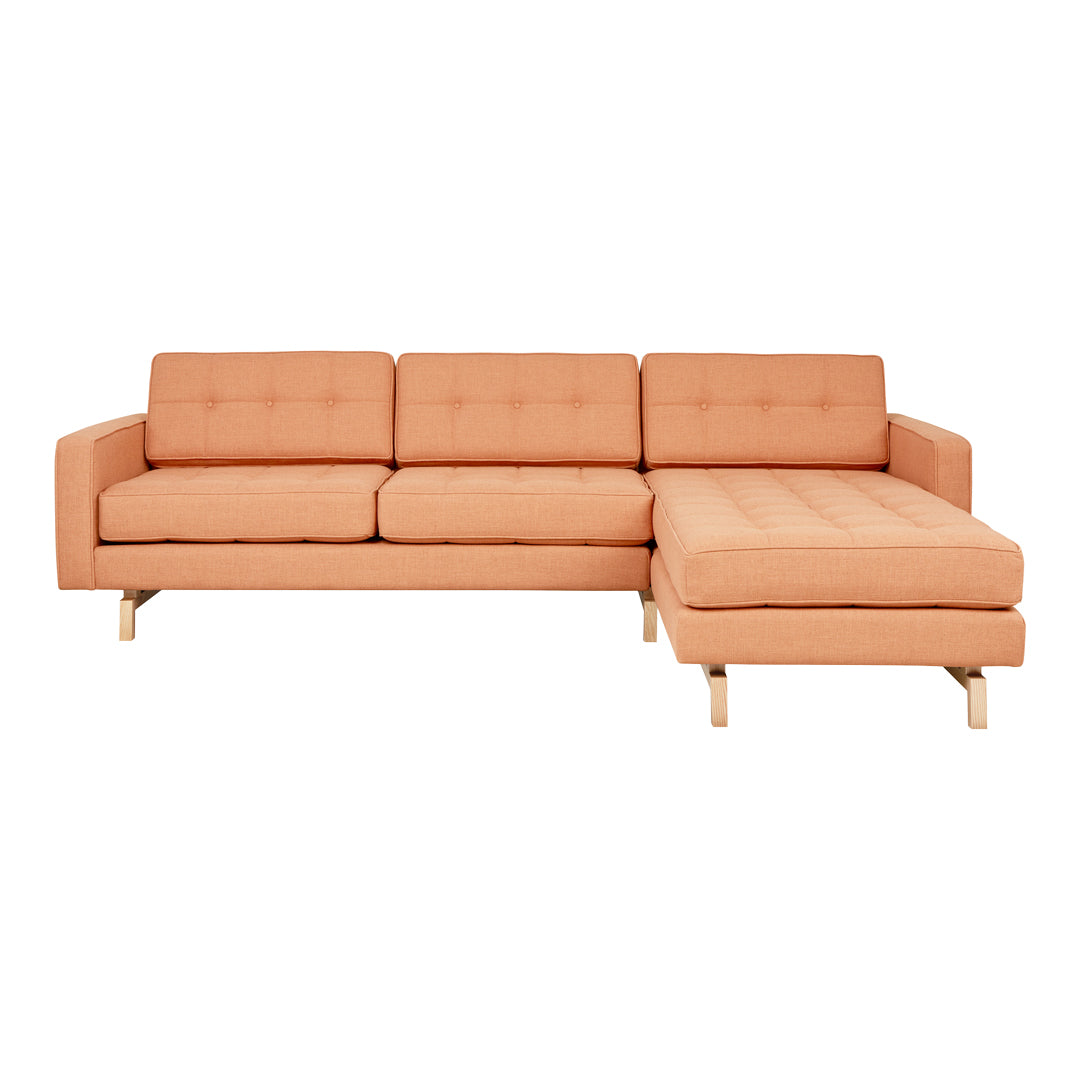 Modern light peach sectional sofa with button-tufted cushions and natural wooden legs, perfect for stylish living spaces.