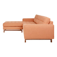 Peach-colored sectional sofa with a modern design and tufted upholstery, featuring wooden legs.