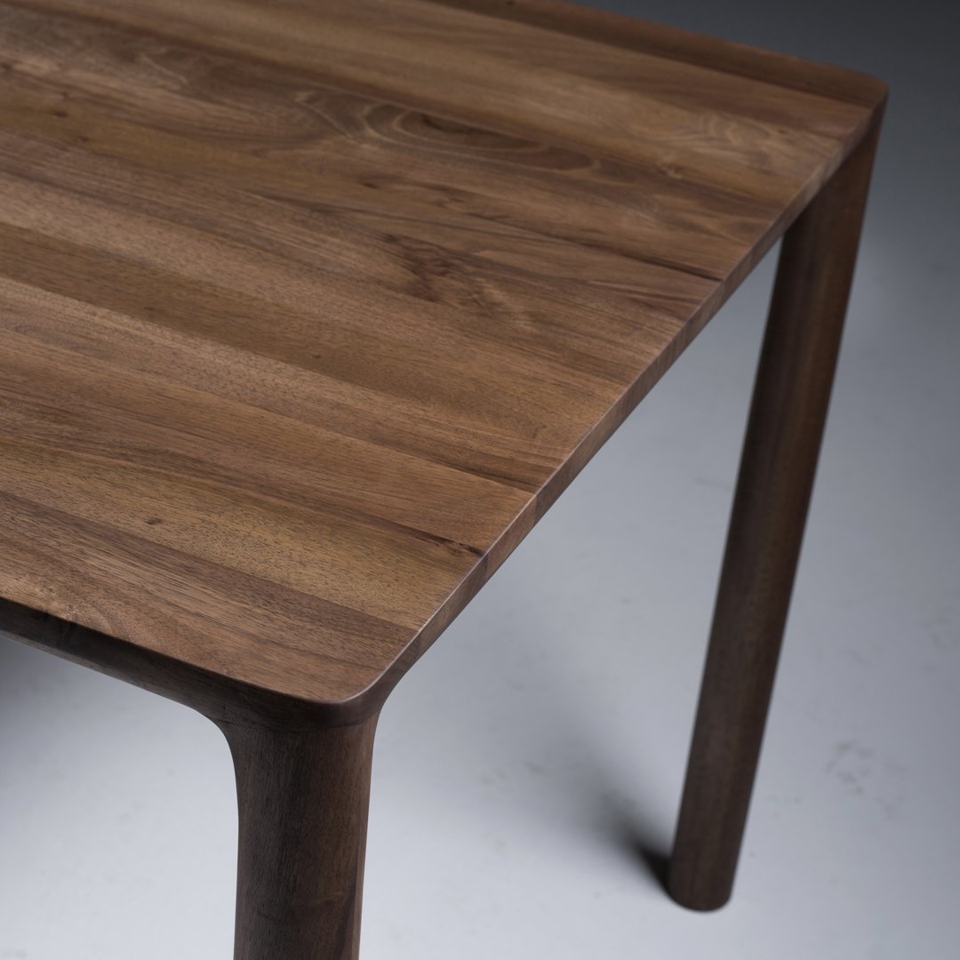 Wooden table with rich walnut tones, showcasing smooth grain patterns and a sleek modern design.