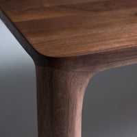 Dark walnut wood tabletop with smooth, rounded edges and a rich, natural grain pattern. Elegant and sturdy design.
