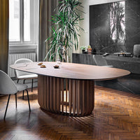 Elegant oval wooden table with a warm walnut finish, featuring a unique slatted base and rich herringbone flooring.