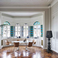 Bright turquoise and blue stained glass windows contrast with sleek white walls and warm wooden flooring, creating a vibrant space.