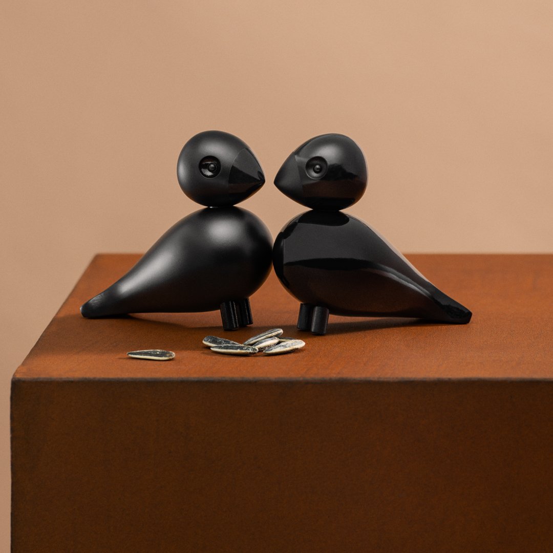 Black bird figurines with smooth, rounded shapes against a warm brown backdrop, complemented by silver accents.