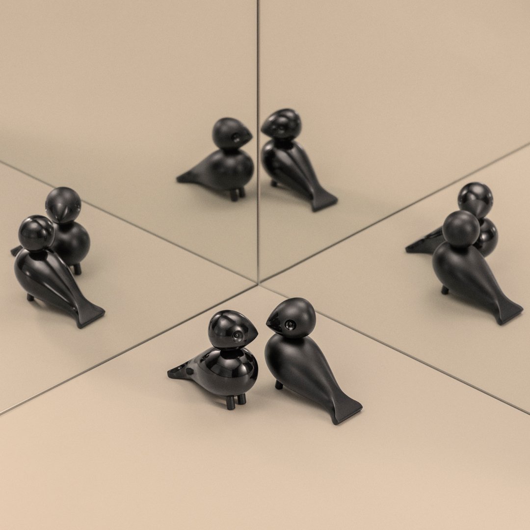 Black decorative figurines with smooth finishes and playful shapes, set against a beige background and mirrored surfaces.