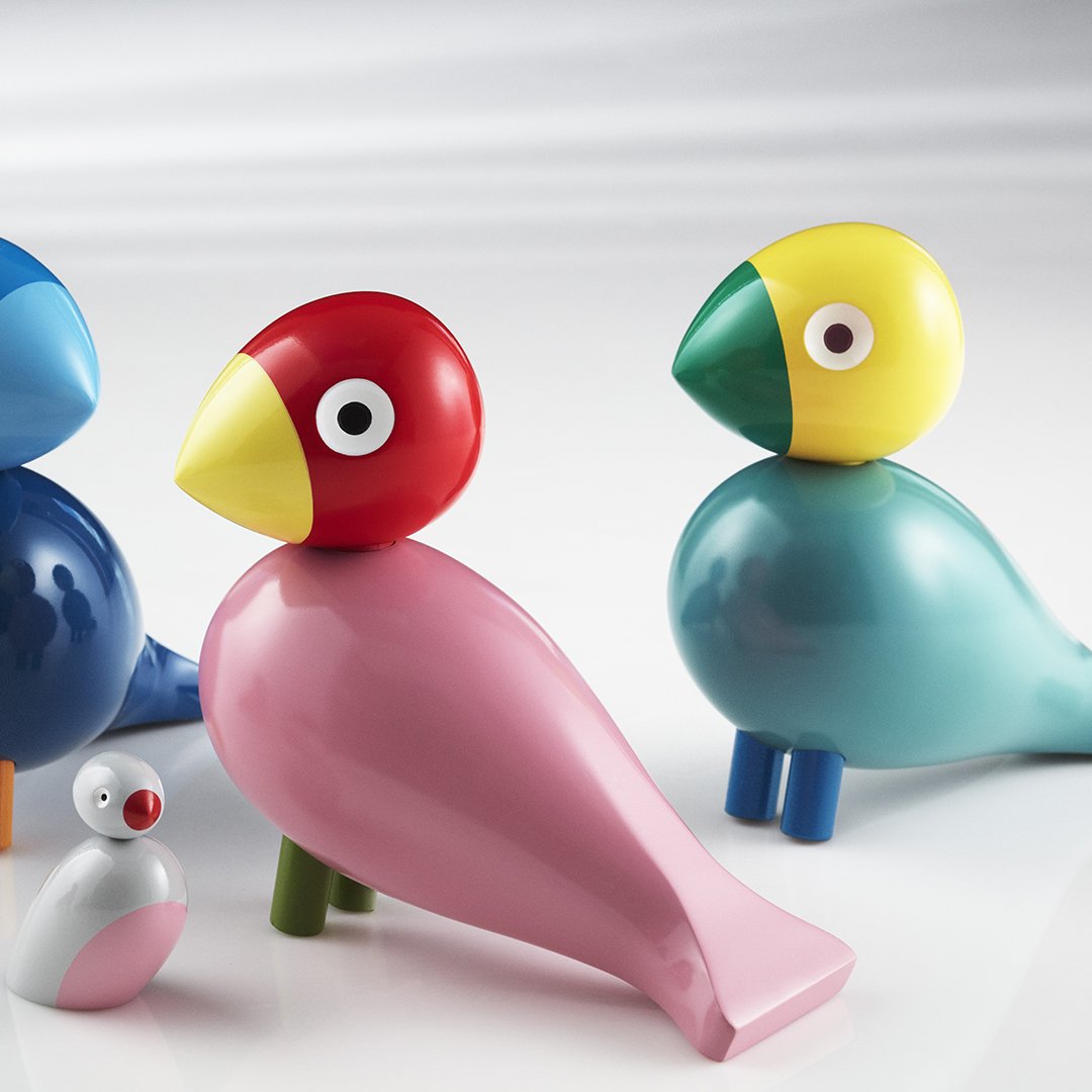 Colorful wooden bird figurines in blue, red, yellow, and pink with smooth, glossy finishes and playful designs.