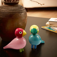 Colorful toy birds in pink, red, yellow, and blue, featuring smooth, rounded shapes and playful expressions.