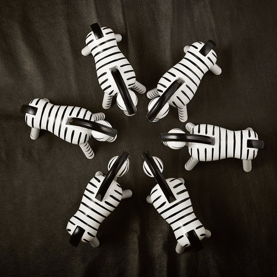 Set of seven black and white striped zebra figurines arranged in a circular pattern on a dark background.