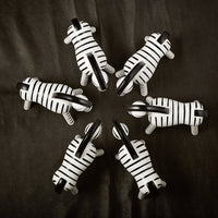 Set of seven black and white striped zebra figurines arranged in a circular pattern on a dark background.