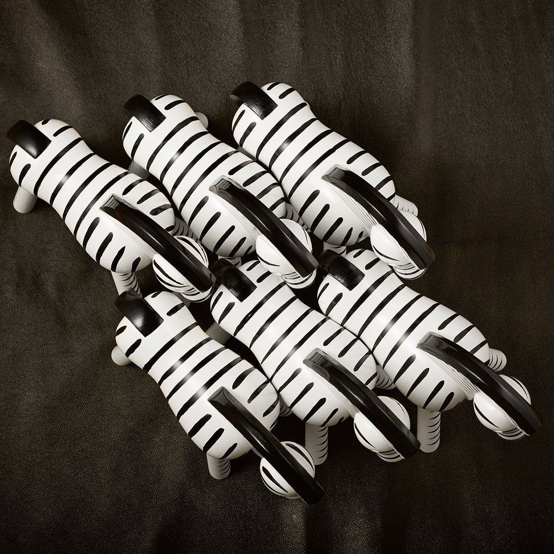 Black and white striped animal figurines arranged in a playful pattern on a dark background.