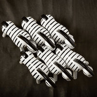 Black and white striped animal figurines arranged in a playful pattern on a dark background.