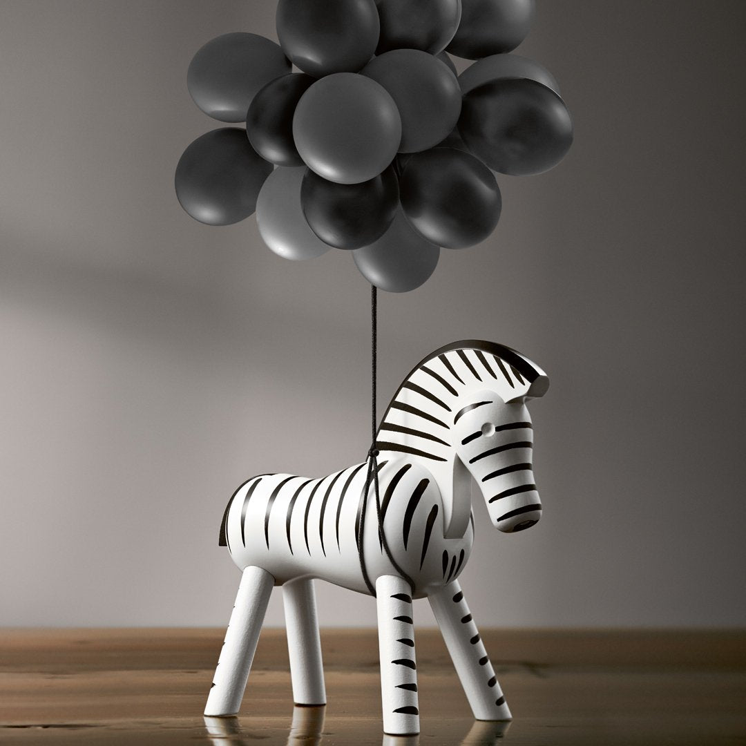 Black and white striped zebra figurine with grey balloon cluster, modern minimalist decor.