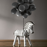 Black and white striped zebra figurine with grey balloon cluster, modern minimalist decor.