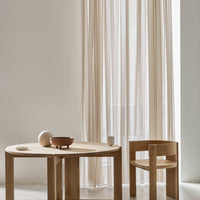 Natural beige curtains with vertical stripes, complemented by a light wooden table and chair in a minimalist setting.
