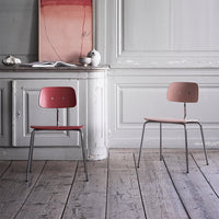 "Two modern chairs in soft pink tones with minimalist design, set against a light wooden floor and neutral walls."