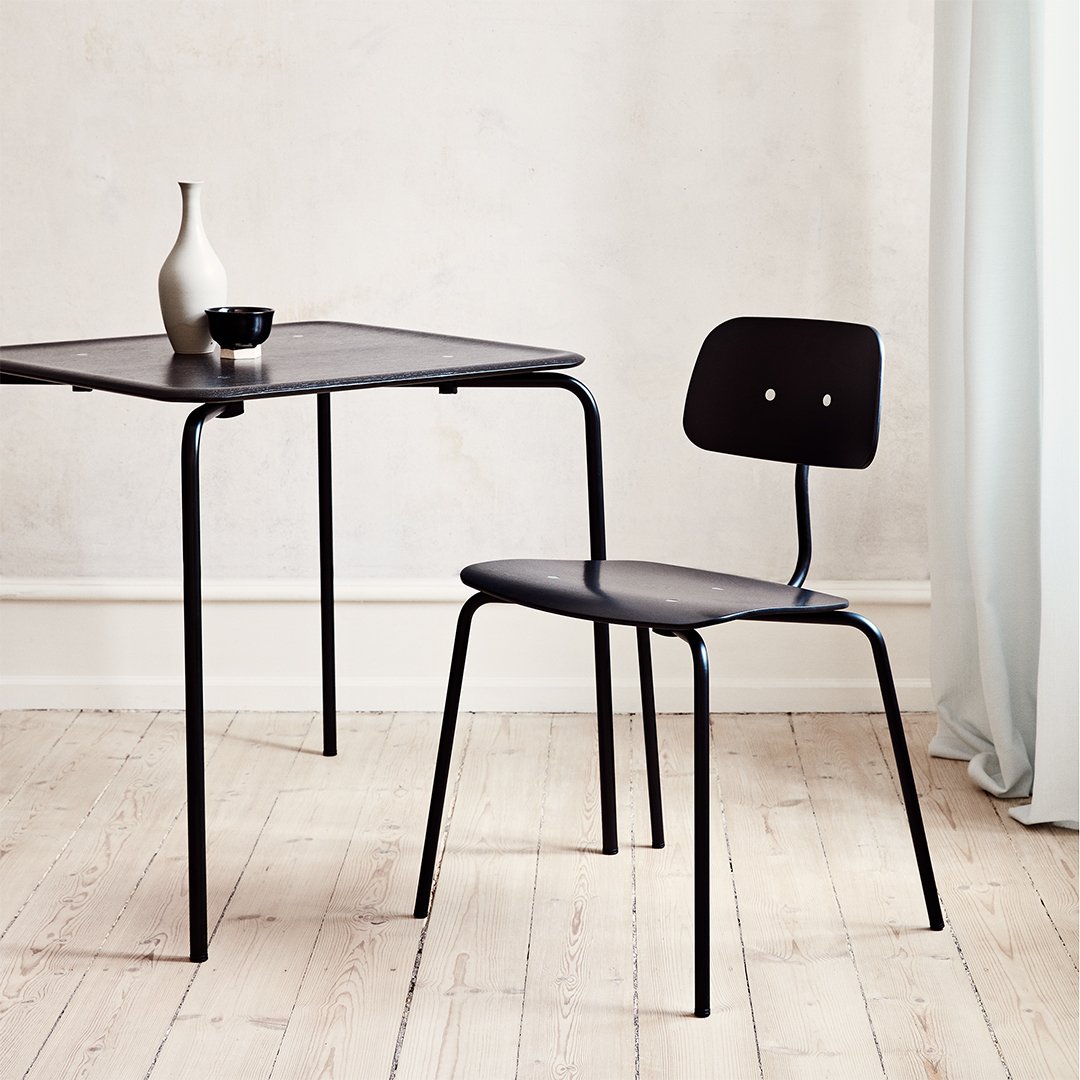 "Minimalist black dining chair and table on a light wooden floor, featuring clean lines and modern design."