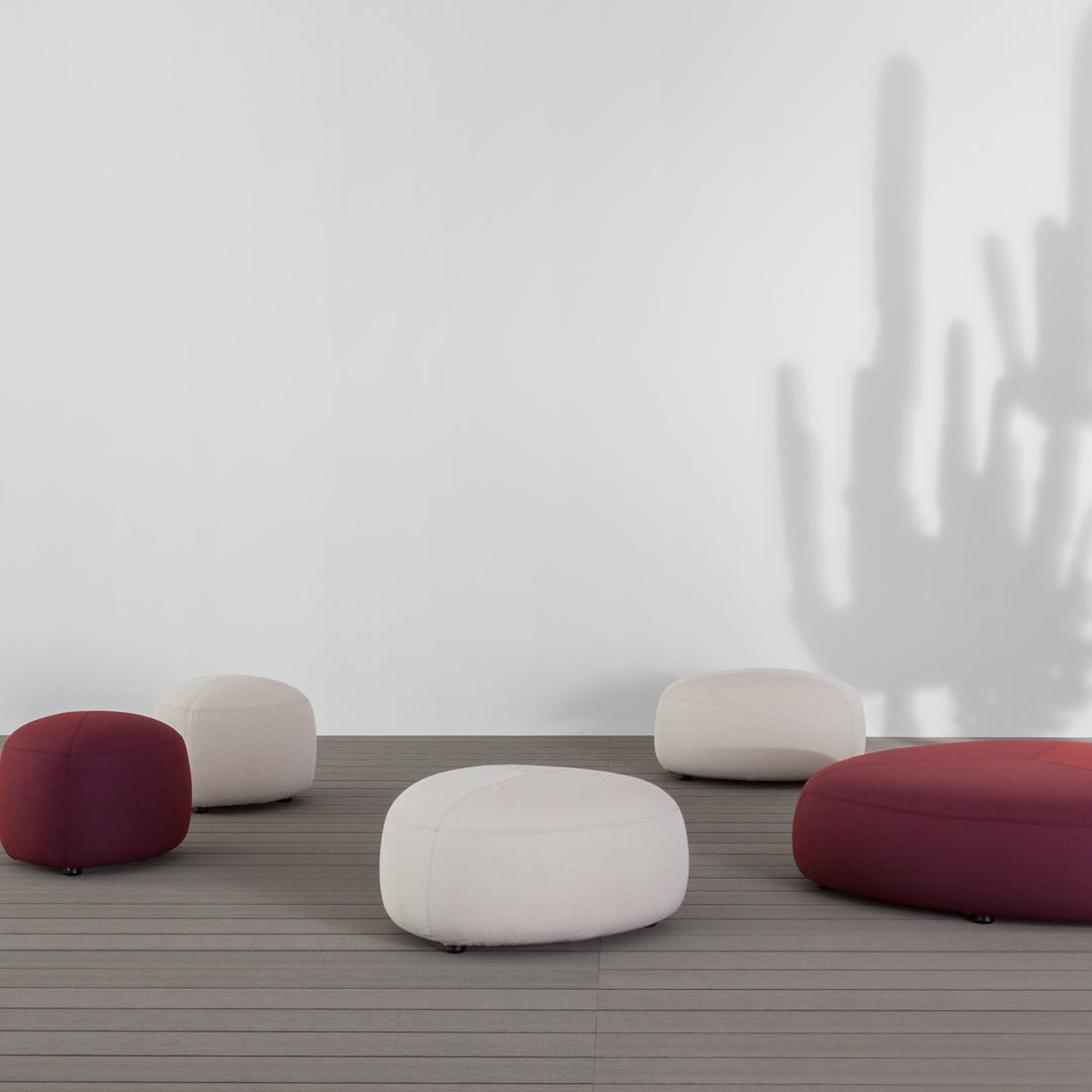 Multicolored poufs in deep maroon and neutral beige tones, featuring soft, rounded shapes on a modern floor setting.