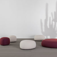 Multicolored poufs in deep maroon and neutral beige tones, featuring soft, rounded shapes on a modern floor setting.