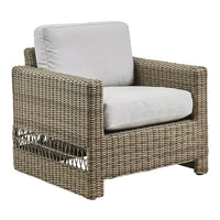 Natural brown woven rattan armchair with light gray cushions, featuring a modern, textured design.