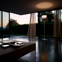 Modern room featuring soft beige tones, sheer light curtains, and a sleek silver lamp against a dark, polished floor.