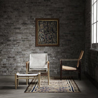 "Neutral-toned chairs with geometric patterns, set against a textured grey brick wall and a patterned area rug."