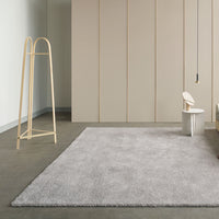 Soft gray shag rug on a sleek concrete floor, enhancing modern minimalism with a subtle texture. Perfect for any space.