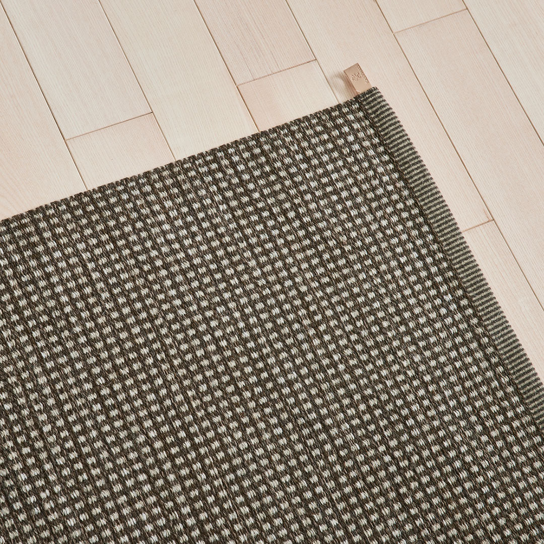 Dark brown mat with a textured pattern of small, light dots, perfect for adding warmth to any space.