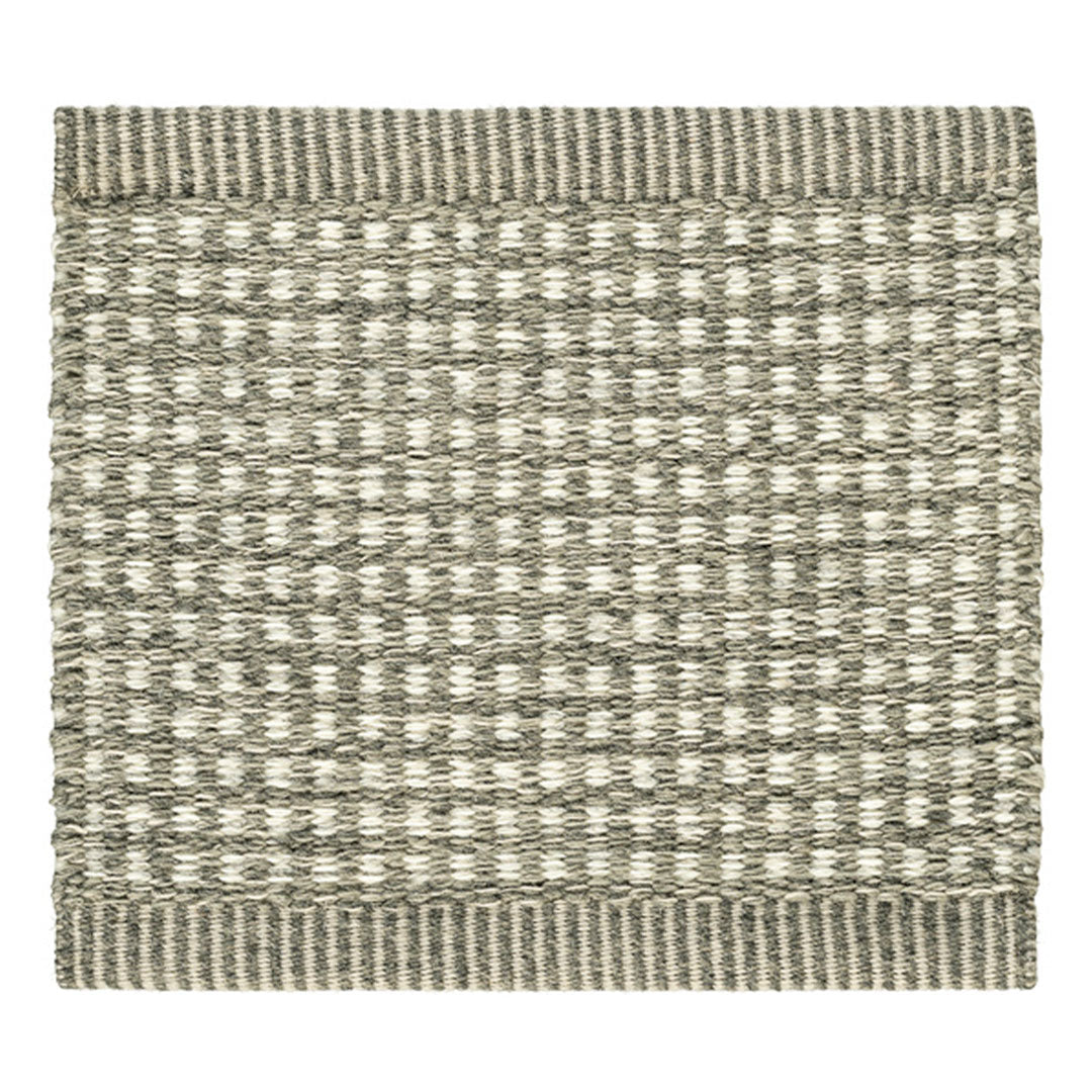 Textured rug in neutral tones of gray and cream, featuring a woven pattern and striped border.