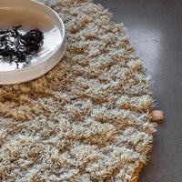 Round beige rug with textured cream pattern, complementing a sleek, modern setting. Perfect for cozy decor.
