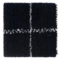 Navy blue rug with white abstract pattern, featuring a textured, fluffy surface and a grid design.