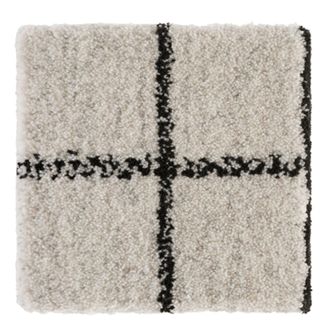 Cream shag rug with black geometric pattern, featuring a bold cross design for modern decor.