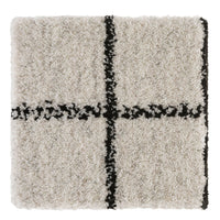 Cream shag rug with black geometric pattern, featuring a bold cross design for modern decor.