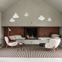 Cozy living room featuring a checkered brown and white rug, soft beige chairs, and modern pendant lights.