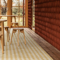 "Beige and yellow checkered rug with warm, earthy red wooden wall in a modern interior setting."
