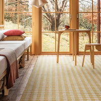 Yellow and white checkered rug in a bright room with wooden accents and neutral furnishings.