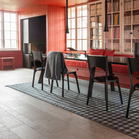 "Blue and white checkered rug on light gray floor, featuring warm red accents in a stylish dining room setting."