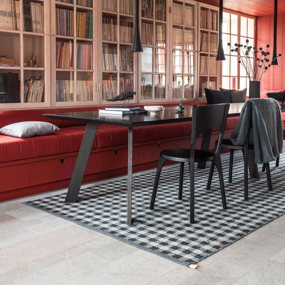 Black and white checkered rug on a light floor, with a red seating area and bookshelves in the background.