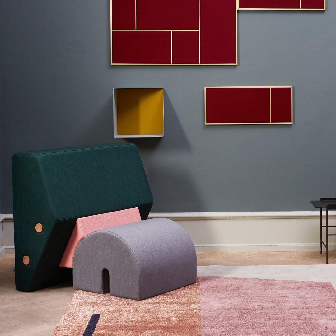 Green and pink geometric furniture with soft gray accents against a neutral wall and vibrant red and yellow artwork.