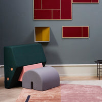 Green and pink geometric furniture with soft gray accents against a neutral wall and vibrant red and yellow artwork.