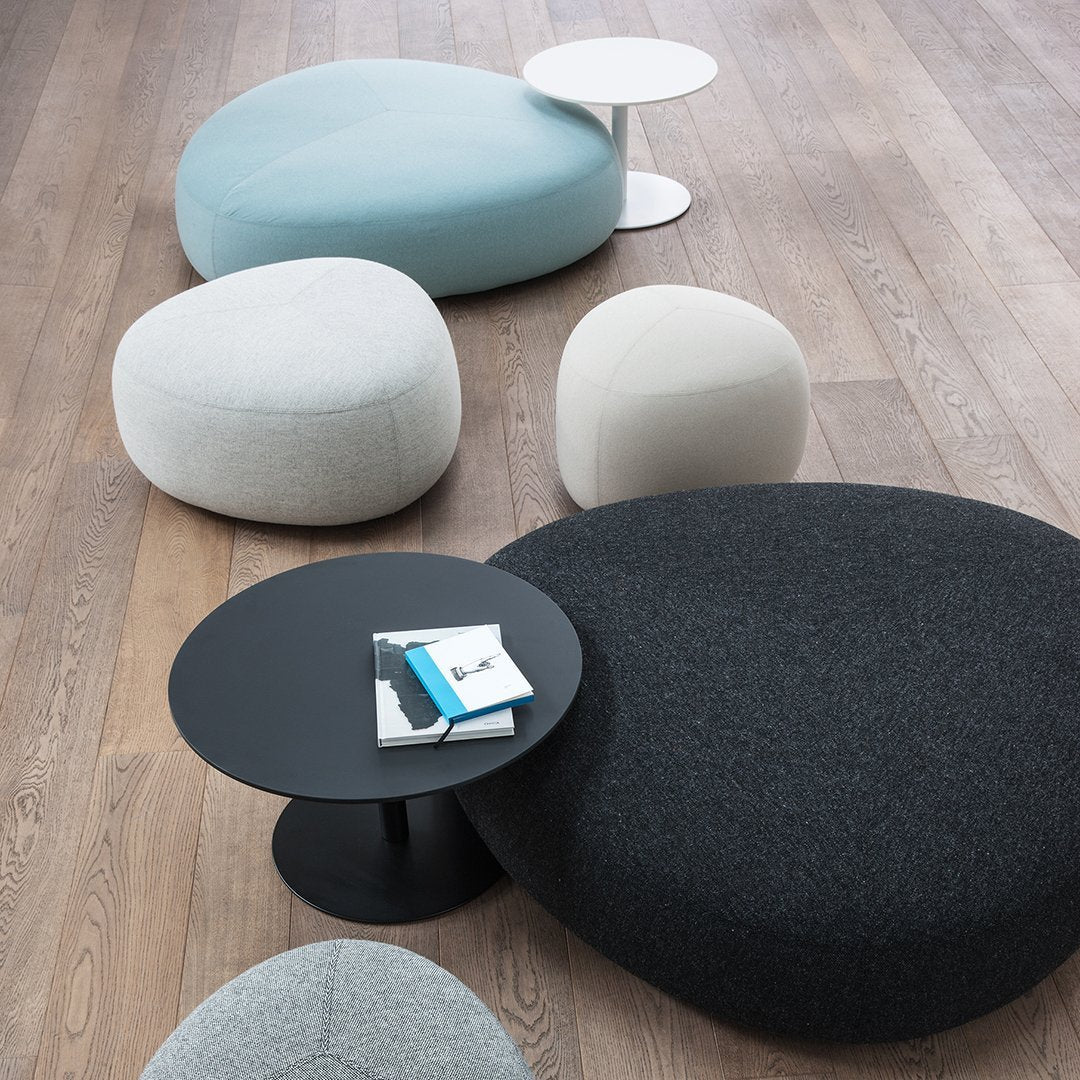 Soft, rounded seating in light blue, gray, and black with a sleek black side table on wooden floor.