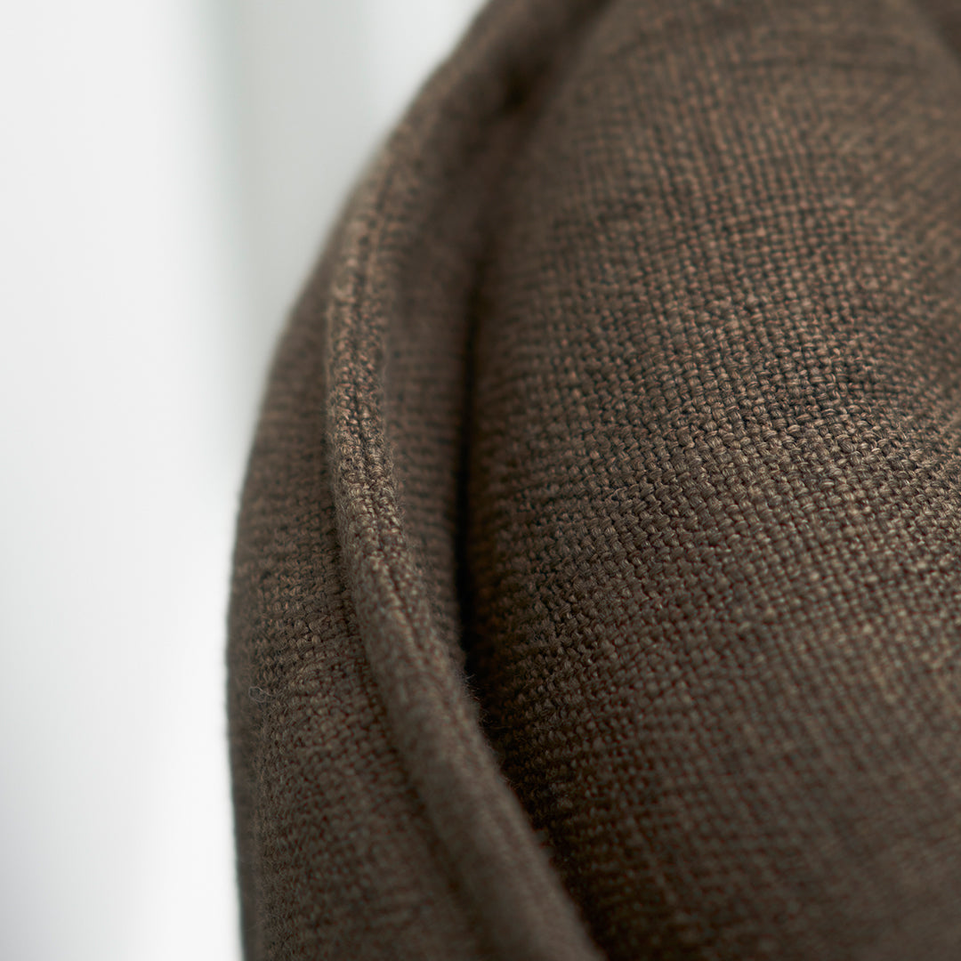 Close-up of textured brown fabric with subtle, rich tones and a smooth, rounded edge detail. Perfect for home decor.