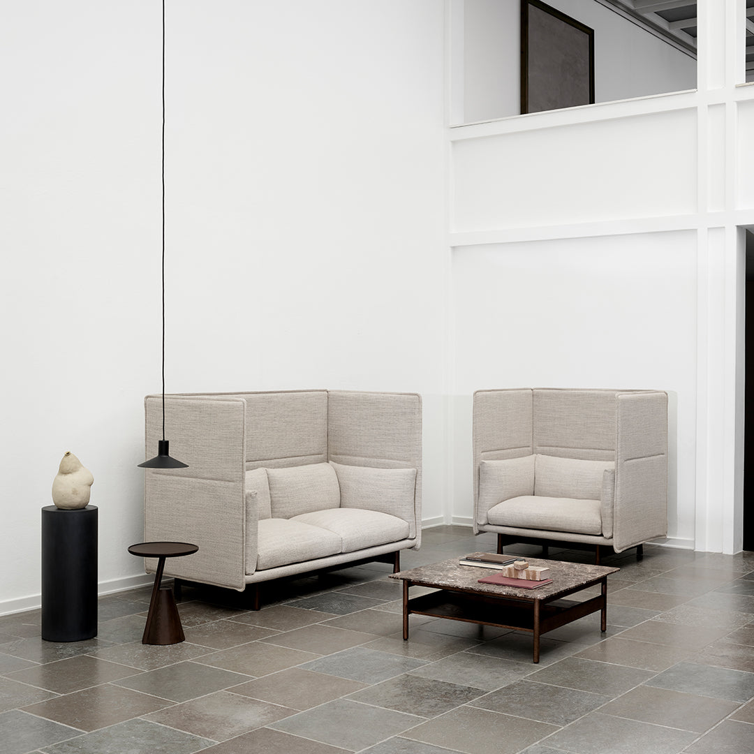 Beige fabric accent chairs with a textured pattern, set against a neutral background and slate tile flooring.