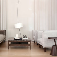Neutral tones with soft gray armchairs, a dark wood coffee table, and light curtains create a modern, serene living space.