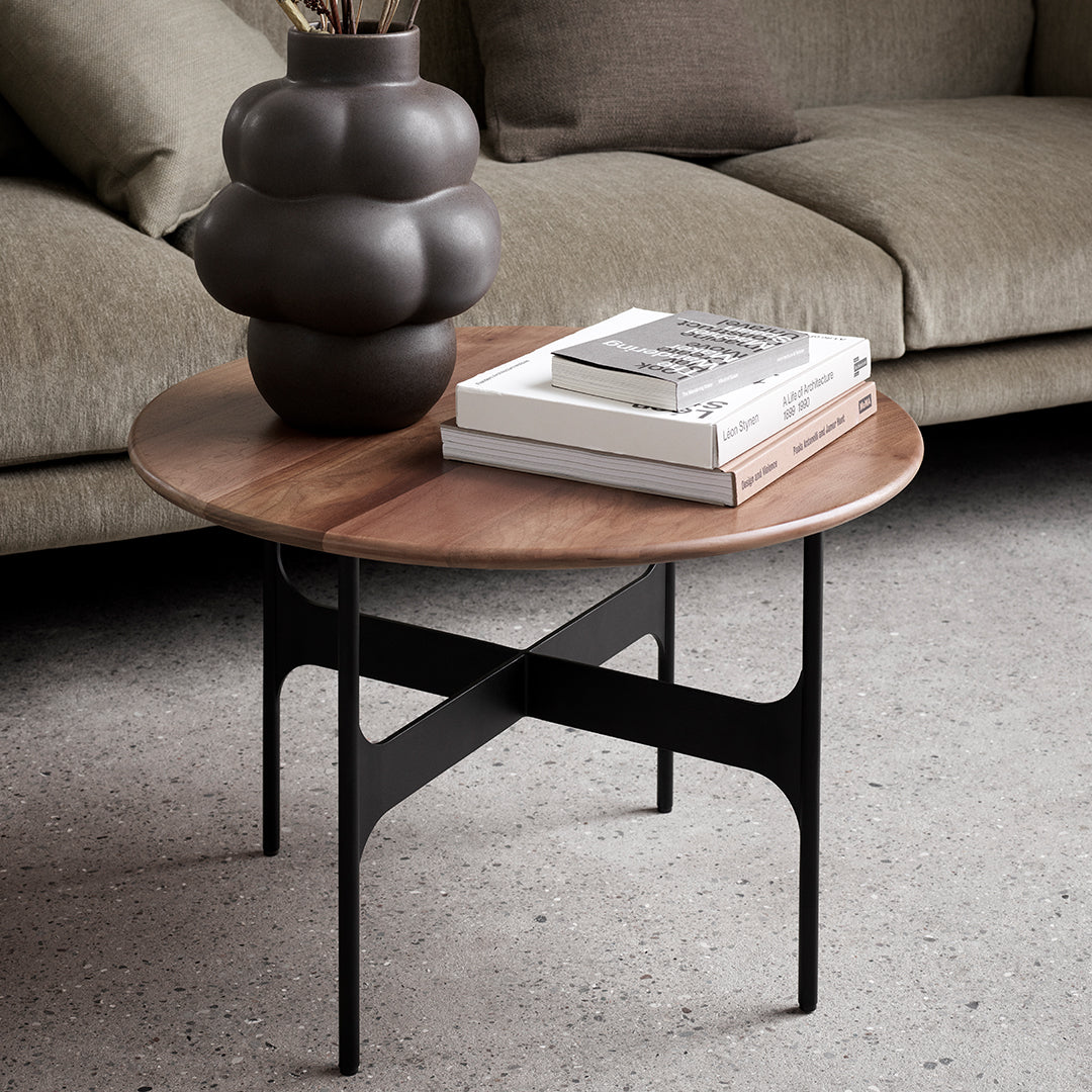 Round wooden coffee table with a walnut finish and sleek black metal legs, complementing modern decor.