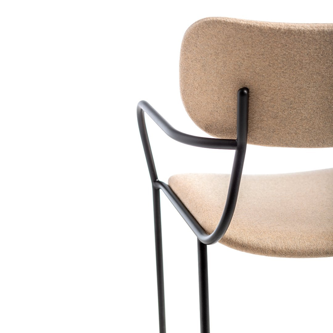 Tan upholstered chair with curved backrest and sleek black metal frame, minimalist design with smooth textures.