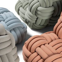 Knotted cushions in muted blue, green, gray, and soft terracotta hues with textured patterns.